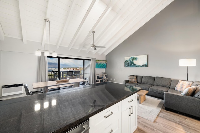 kitchen with light wood-type flooring, beam ceiling, white cabinets, dark stone counters, and ceiling fan