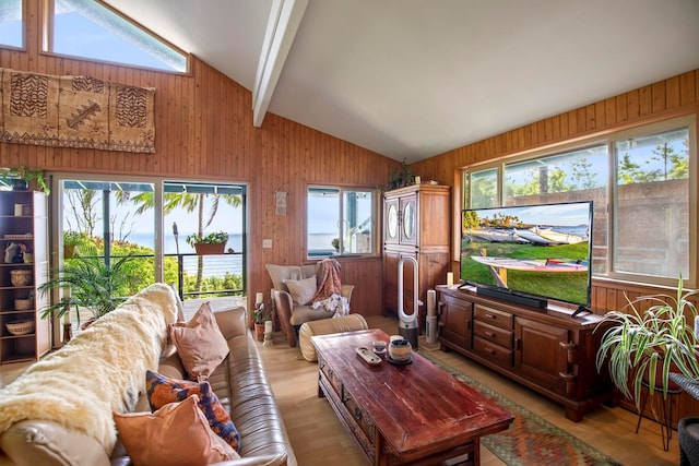 living room with wood walls, light wood-type flooring, and lofted ceiling with beams