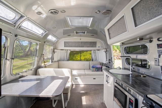 kitchen with dark wood-type flooring, white cabinets, stainless steel microwave, and sink