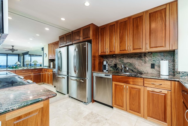 kitchen featuring dark stone counters, sink, ceiling fan, appliances with stainless steel finishes, and tasteful backsplash