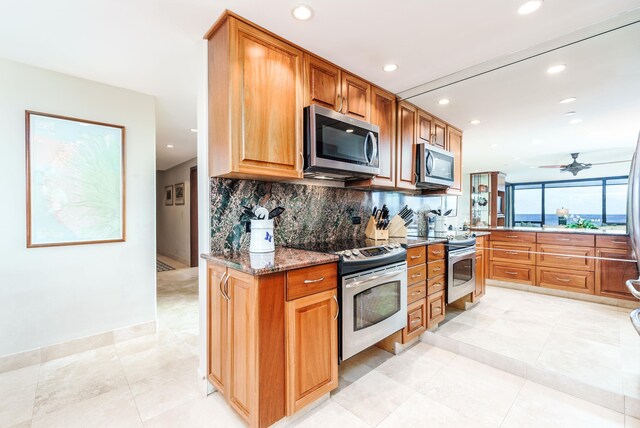 kitchen featuring dark stone counters, ceiling fan, decorative backsplash, light tile patterned floors, and stainless steel appliances