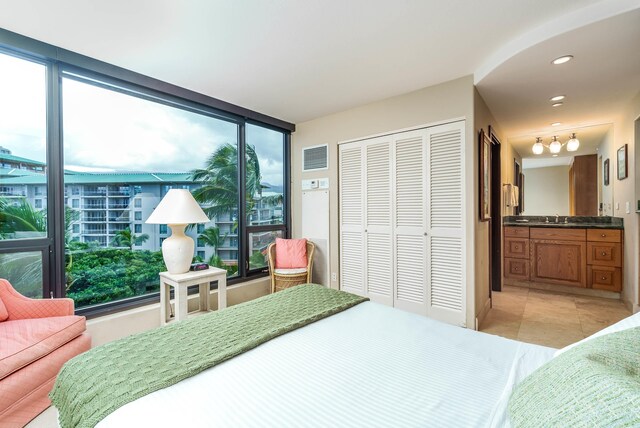 bedroom with a closet, light tile patterned floors, and sink