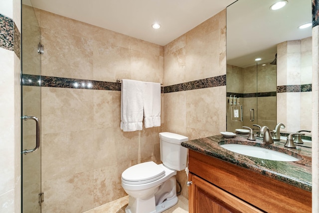 bathroom featuring walk in shower, vanity, toilet, and tile walls