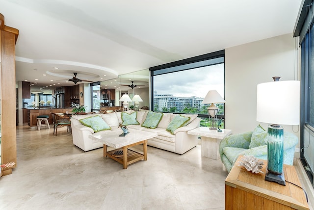 living room featuring ceiling fan and expansive windows