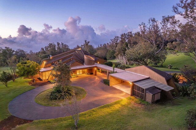 2450 Piiholo Rd, Makawao, HI 96768 - back of property at dusk with curved driveway, a yard, an outdoor structure, and a carport