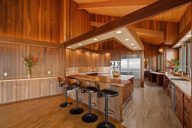 2450 Piiholo Rd, Makawao, HI 96768 - kitchen with stainless steel appliances, a sink, wood walls, wood finished floors, and brown cabinetry