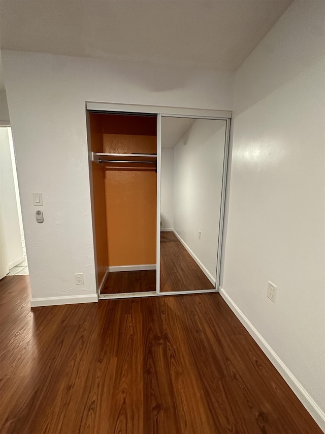 unfurnished bedroom with a closet and dark hardwood / wood-style floors