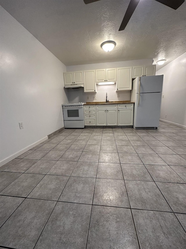 kitchen featuring white appliances, sink, ceiling fan, light tile patterned floors, and a textured ceiling