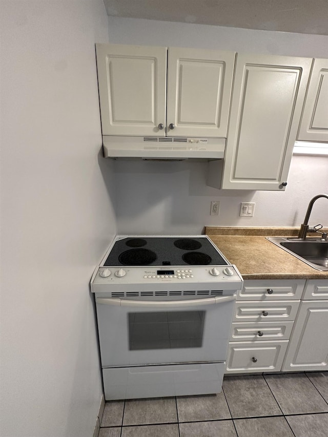 kitchen with light tile patterned floors, sink, white cabinetry, and electric stove