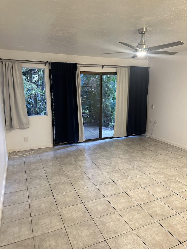 empty room featuring light tile patterned floors, a textured ceiling, and ceiling fan