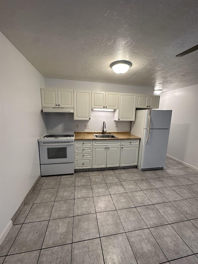 kitchen featuring a textured ceiling, white appliances, sink, and light tile patterned floors