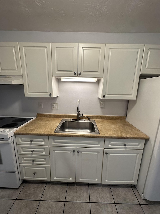 kitchen with tile patterned floors, white appliances, white cabinetry, and sink