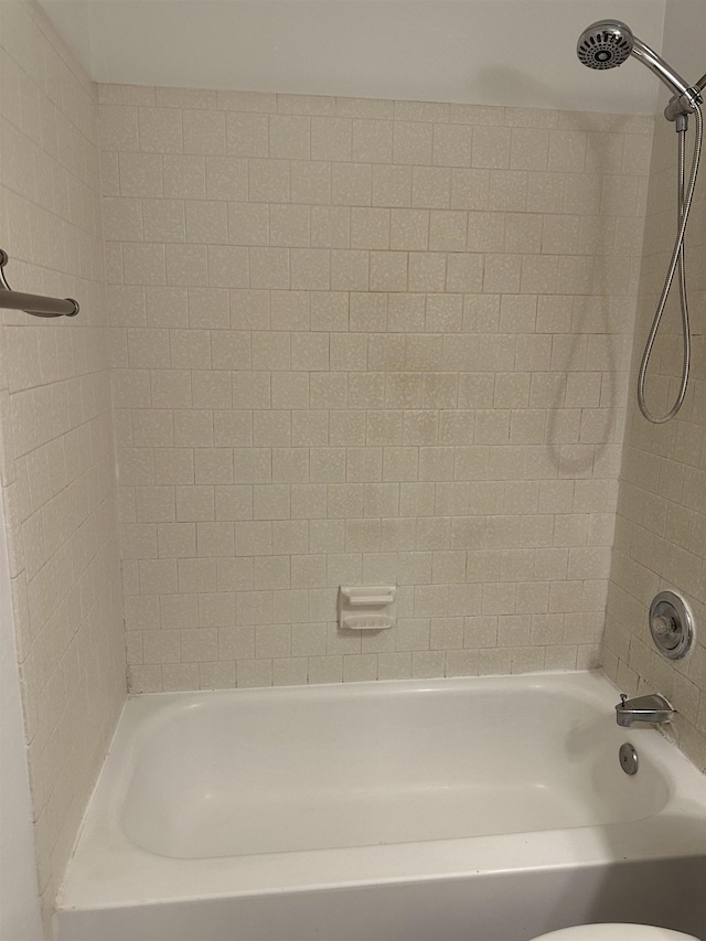 bathroom featuring tiled shower / bath combo and toilet