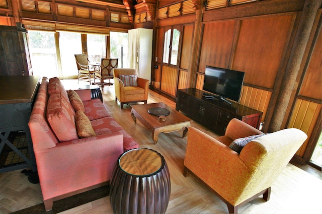 living room featuring wood walls, light parquet flooring, and a wealth of natural light