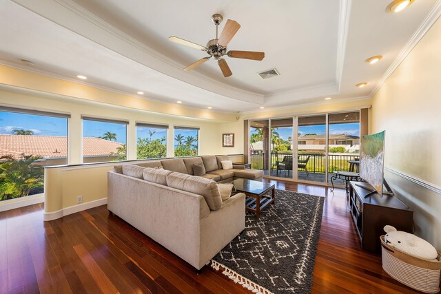 living room featuring ceiling fan, dark hardwood / wood-style flooring, ornamental molding, and a tray ceiling