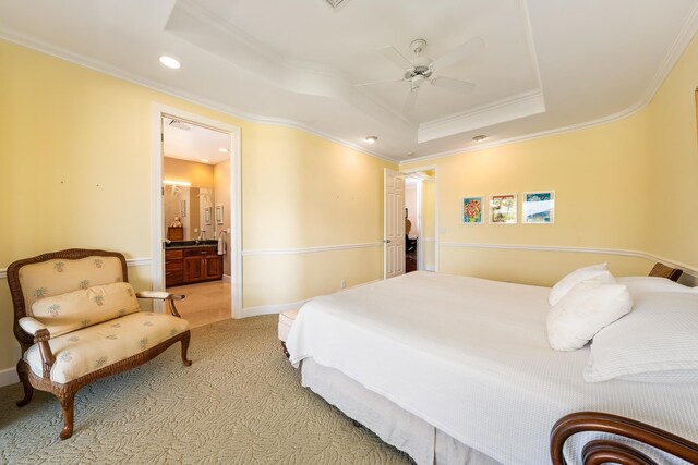 bedroom featuring ensuite bath, crown molding, light colored carpet, ceiling fan, and a raised ceiling