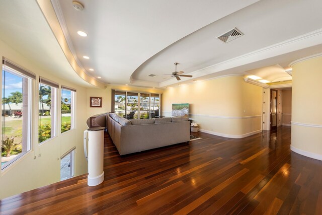 living room featuring ceiling fan, a wealth of natural light, dark hardwood / wood-style floors, and a tray ceiling