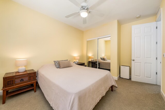 bedroom with ceiling fan, light colored carpet, and a closet