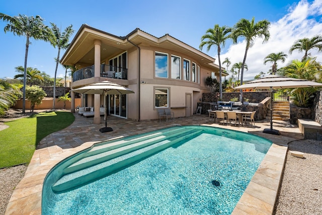 back of property with a balcony, a fenced in pool, and a patio area