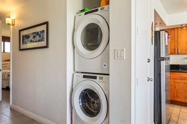 clothes washing area with light tile patterned floors and stacked washer and clothes dryer