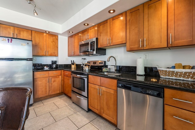 kitchen featuring light tile patterned floors, sink, appliances with stainless steel finishes, and dark stone counters