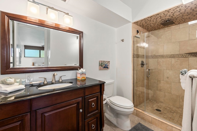 bathroom featuring toilet, a shower with door, vanity, and tile patterned flooring