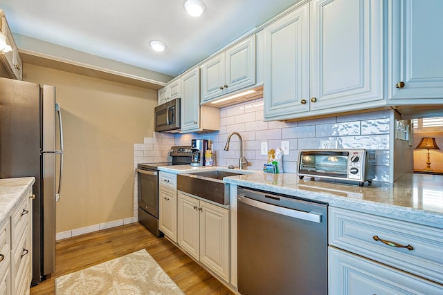 kitchen featuring white cabinetry, sink, light hardwood / wood-style floors, and appliances with stainless steel finishes