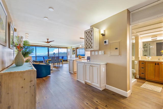 kitchen with pendant lighting, electric panel, ceiling fan, light wood-type flooring, and kitchen peninsula