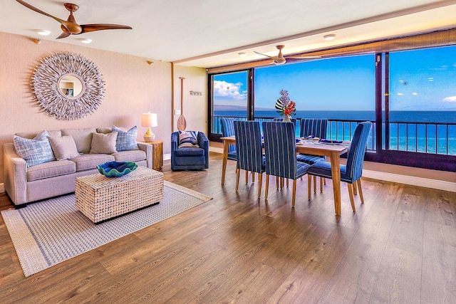 dining space with floor to ceiling windows, ceiling fan, a water view, and wood-type flooring