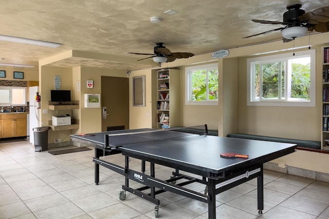 recreation room featuring ceiling fan, sink, and light tile patterned floors