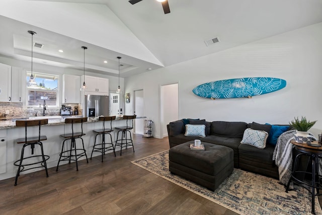 living room with sink, dark hardwood / wood-style floors, a raised ceiling, a towering ceiling, and ceiling fan