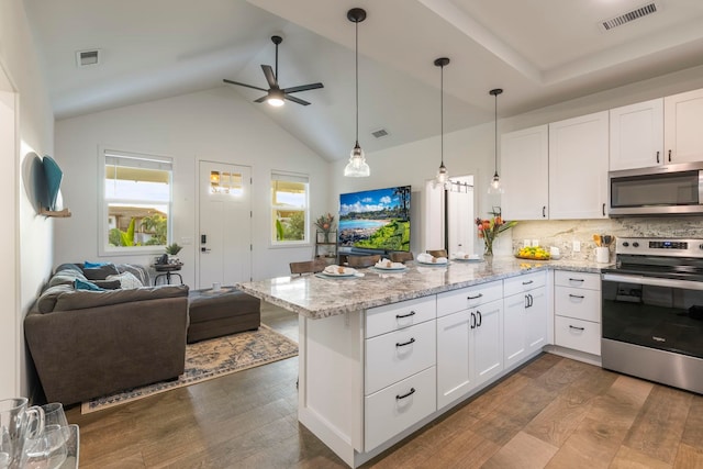 kitchen featuring stainless steel appliances, white cabinetry, light stone countertops, and kitchen peninsula