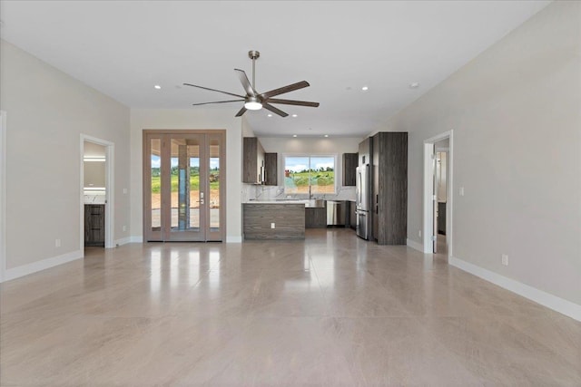 unfurnished living room featuring ceiling fan and sink