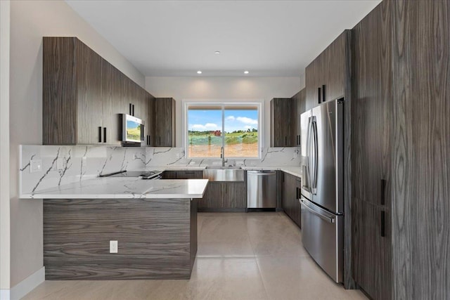 kitchen with sink, appliances with stainless steel finishes, light stone counters, tasteful backsplash, and kitchen peninsula