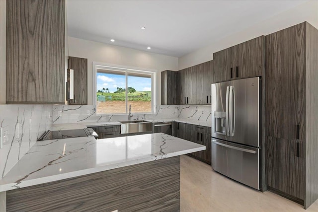 kitchen with sink, stainless steel fridge, backsplash, light stone countertops, and kitchen peninsula