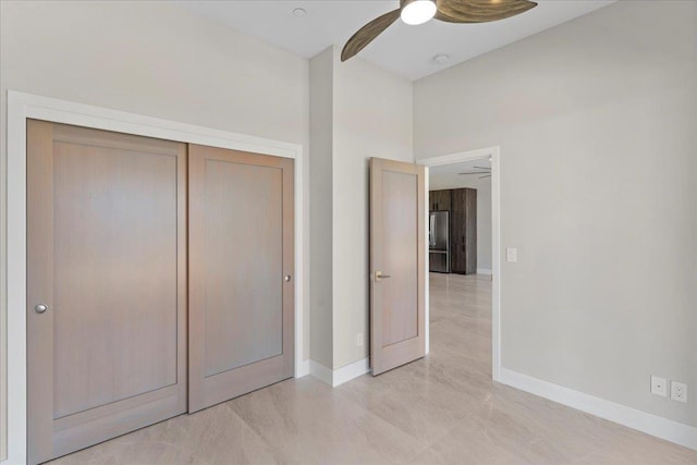 unfurnished bedroom with stainless steel fridge, ceiling fan, and a closet