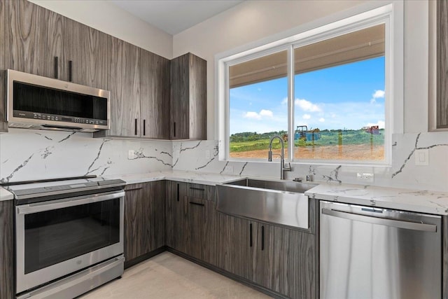 kitchen with light stone countertops, appliances with stainless steel finishes, sink, and decorative backsplash