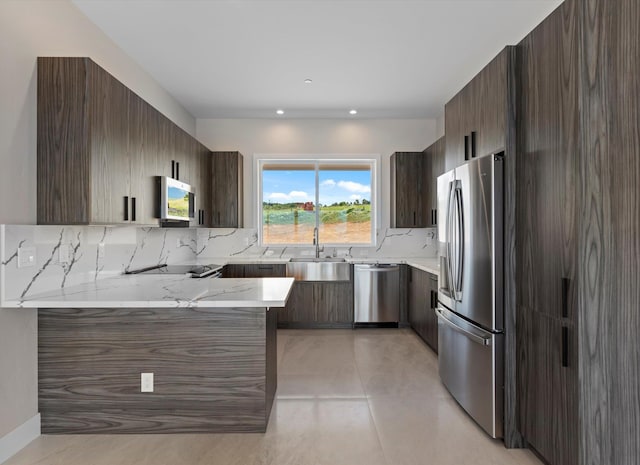 kitchen featuring sink, decorative backsplash, light stone countertops, and appliances with stainless steel finishes