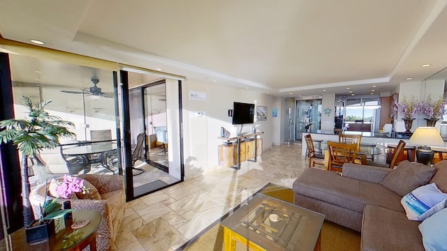 living room with a raised ceiling and ceiling fan