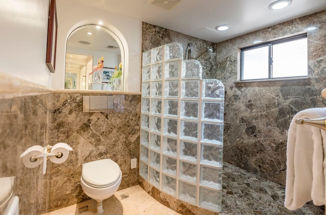 bathroom featuring tile walls, toilet, a tile shower, and tile flooring