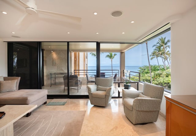 living room with floor to ceiling windows, ceiling fan, and a water view