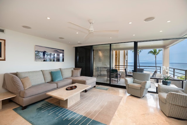 living room with ceiling fan, a water view, light tile flooring, and a wall of windows