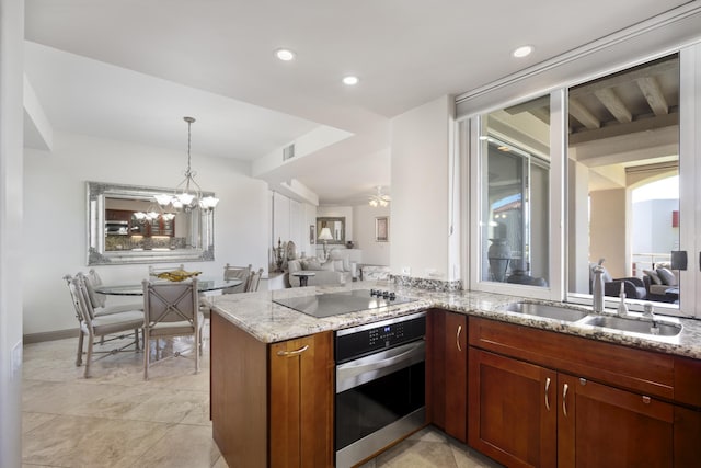 kitchen with light stone counters, black electric stovetop, open floor plan, a sink, and oven