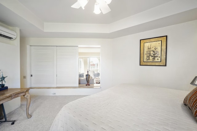 carpeted bedroom featuring a closet, a wall mounted AC, a raised ceiling, and a ceiling fan