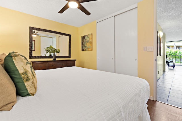 bedroom featuring ceiling fan, wood-type flooring, a closet, and a textured ceiling