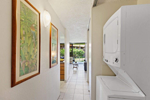 washroom with light tile patterned floors, stacked washer / dryer, and a textured ceiling