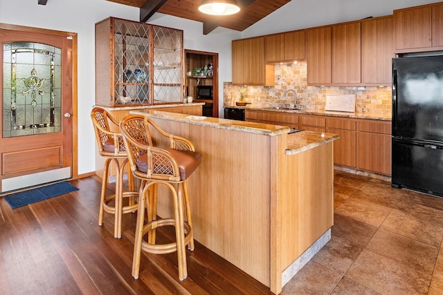 kitchen with a kitchen island, tasteful backsplash, sink, a breakfast bar area, and black appliances