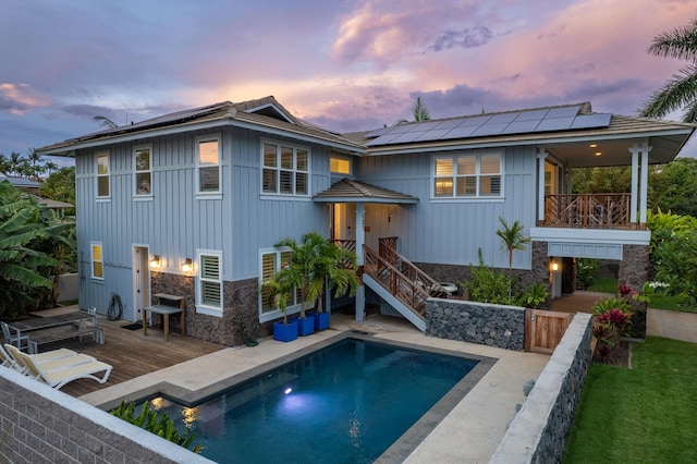 137 Hoohale St, Kihei, HI 96753 - back of house at dusk with board and batten siding, an outdoor pool, stone siding, and solar panels