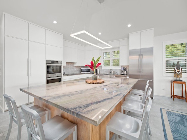 137 Hoohale St, Kihei, HI 96753 - kitchen with a large island, tasteful backsplash, stainless steel appliances, and white cabinetry