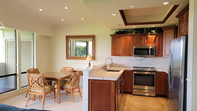 kitchen with kitchen peninsula, tasteful backsplash, stainless steel appliances, sink, and light tile patterned flooring